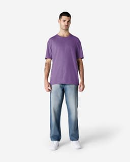 A man wearing a purple Gildan Softstyle adult t-shirt and light blue jeans, standing against a plain background.