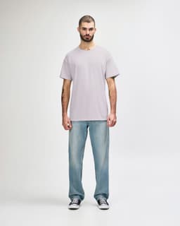 A light grey Gildan Softstyle adult t-shirt worn with blue jeans, featuring a logo on the t-shirt.