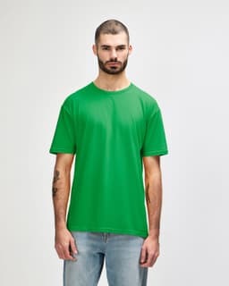 A green Gildan Softstyle adult t-shirt displayed on a model, featuring a plain design and a label.
