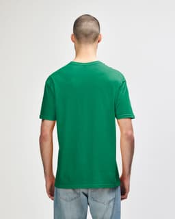 A green Gildan Softstyle adult T-shirt displayed on a person from the back, featuring a plain design.