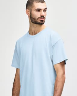 A light blue Gildan Softstyle adult t-shirt featuring short sleeves and a round neckline, modelled by a male.