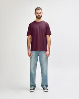 A maroon adult T-shirt displayed on a mannequin, paired with light blue jeans and white shoes. The T-shirt has a logo.