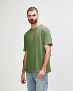 An olive green Gildan Softstyle adult t-shirt worn by a male model, featuring a simple design and a logo.