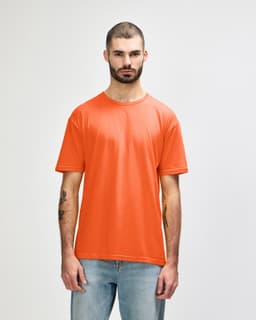 An orange Gildan Softstyle adult T-shirt on a model, featuring a simple design and a crew neckline.