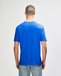A blue Gildan Softstyle adult T-shirt viewed from the back, featuring a plain design and a tag.