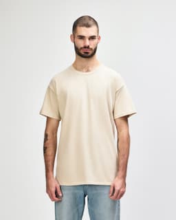 A beige adult t-shirt is displayed worn by a male model, featuring a simple design and short sleeves.
