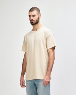 A lightweight, cream-coloured adult t-shirt displayed on a model, featuring a relaxed fit and simple design.