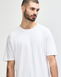 A white Gildan Softstyle adult T-shirt displayed on a model with a neutral background, featuring a logo.