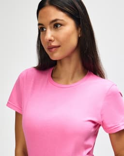 A pink Gildan Softstyle ladies' t-shirt displayed on a model, featuring a round neckline and short sleeves.