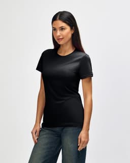 A black Gildan Softstyle ladies' t-shirt displayed on a model, side view, with blue jeans. The shirt has a logo.