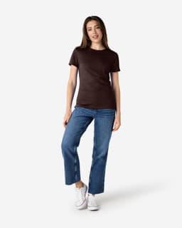 A brown Gildan Softstyle ladies' t-shirt paired with blue jeans and white sneakers, featuring a small logo.