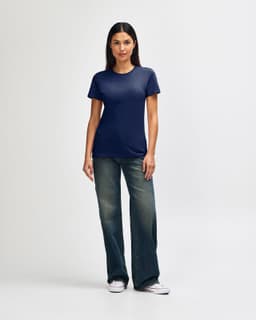 A navy blue ladies' T-shirt paired with light blue jeans and white sneakers. The shirt features a logo.