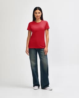 A red Gildan Softstyle ladies' t-shirt paired with blue jeans, worn by a woman standing against a plain background.