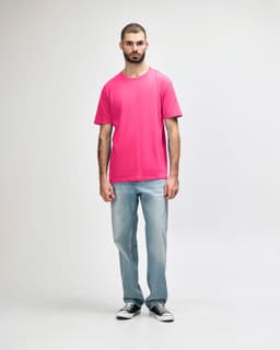 A model wearing a vibrant pink Gildan Softstyle Midweight T-Shirt paired with black jeans and sneakers.