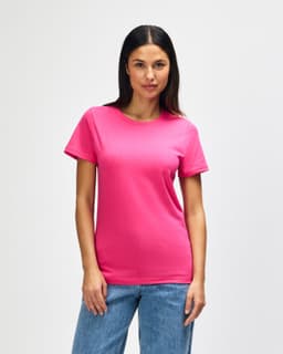 A pink Gildan Softstyle ladies midweight T-shirt displayed on a model, featuring a simple design and a logo.