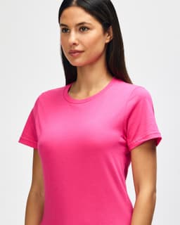 A model wearing a bright pink Gildan Softstyle ladies midweight t-shirt, showcasing a round neckline and short sleeves.