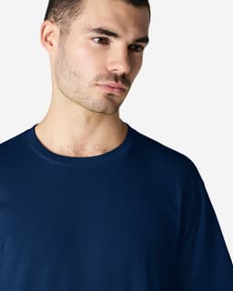 A navy blue softstyle adult t-shirt with a round neckline, worn by a model, featuring a logo.