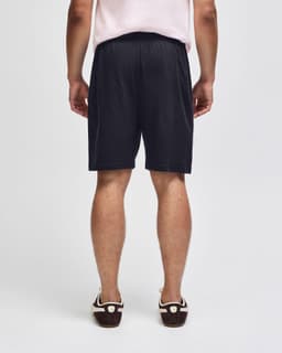 Black gym shorts with an elastic waistband, viewed from the back, featuring a simple design and branding.