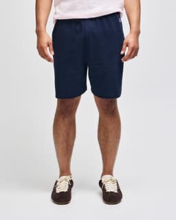 Navy cotton gym shorts with an elastic waistband and a logo, modelled by a person standing upright.