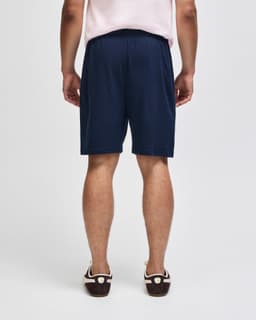 Navy blue gym shorts with an elastic waistband, featuring a logo. View shows the back side of the shorts.