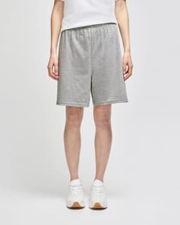 Grey cotton gym shorts with an elastic waistband, featuring a logo and paired with white sneakers.