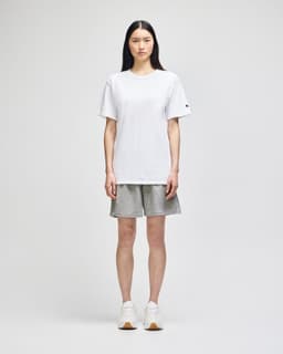 A model wearing grey cotton gym shorts and a white t-shirt, standing against a neutral background.