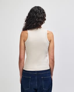 A fitted women's tank top in a light beige colour, featuring a sleeveless design and fitted silhouette.