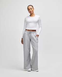 A fitted white long-sleeve crop top paired with grey wide-leg trousers, featuring pockets and a relaxed fit.