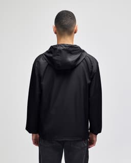 A black packable anorak jacket with a hood, viewed from the back, featuring a logo on the neck area.