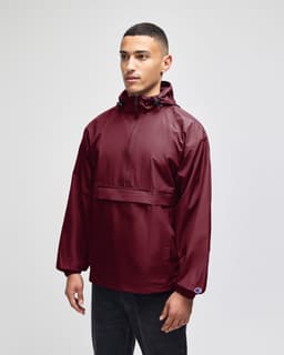 A maroon packable anorak jacket with a hood and a logo, worn by a model standing against a neutral background.