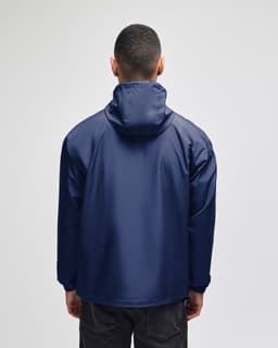 A navy blue packable anorak jacket featuring a hood and a logo on the back. Suitable for rain protection.