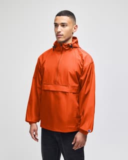 An orange packable anorak jacket with a hood and front pocket, featuring a logo on the sleeve.