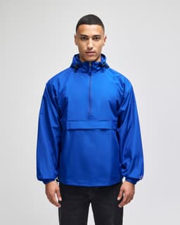A blue packable anorak jacket with a hood and front pocket, featuring a logo on the sleeve.