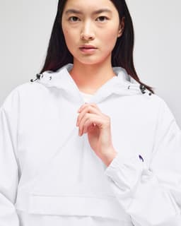 A packable anorak jacket in white, featuring a drawstring hood and a small logo on the sleeve.