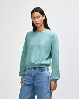 A teal women's crewneck sweatshirt with a relaxed fit and long sleeves, featuring a subtle logo.