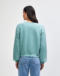A women's crewneck sweatshirt in teal, featuring a relaxed fit and ribbed cuffs, with a logo on the back.