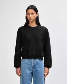 A black women's crewneck sweatshirt with long sleeves and a relaxed fit, featuring a simple design.