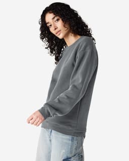 A unisex crewneck sweatshirt in grey, featuring long sleeves and a relaxed fit. It includes a logo.
