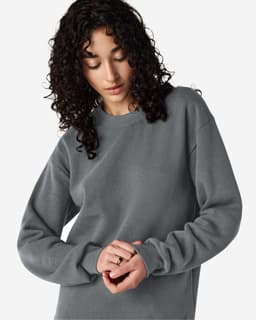 A unisex crewneck sweatshirt in grey featuring long sleeves and a relaxed fit, with a small logo on it.