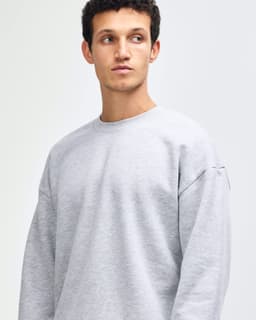 A unisex crewneck sweatshirt in grey, featuring long sleeves and a comfortable fit. It includes a logo.
