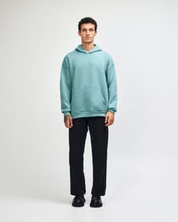 A unisex hooded sweatshirt in mint green, paired with black cargo pants and sneakers, featuring a logo.