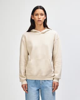A unisex hooded sweatshirt in a light beige colour, featuring a front pocket and a hood. It has a branding logo.