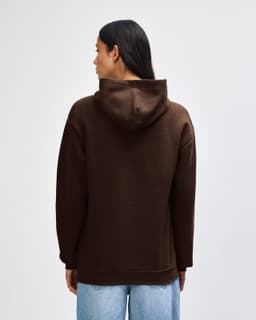 A unisex hooded sweatshirt in brown, featuring a spacious hood and a relaxed fit, with branding on the garment.