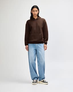 A unisex hooded sweatshirt in brown, featuring a front pocket and paired with black cargo pants.
