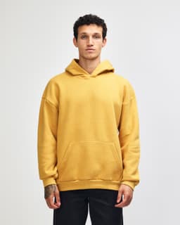A unisex hooded sweatshirt in mustard yellow with a front pocket and a logo.