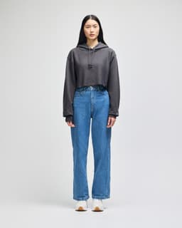 A cropped hoodie in grey with a hood, paired with high-waisted denim jeans and white shoes.