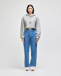 A cropped hoodie in grey with a hood, paired with blue wide-leg jeans and white sneakers.