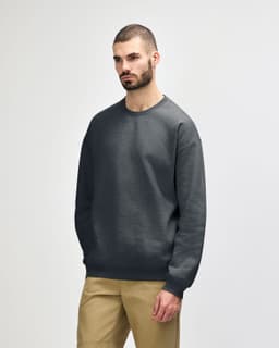 A dark green Gildan Softstyle adult sweatshirt on a model, featuring a casual design and long sleeves.
