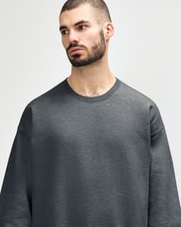 An olive green Gildan Softstyle adult sweatshirt displayed on a male model, featuring a simple design and crew neck.