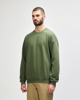 A green Gildan Softstyle adult sweatshirt is displayed on a model, featuring a simple design and a logo.